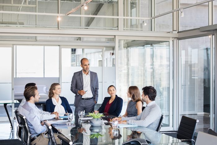 Human resource manager training people about company and future prospects. Group of businesspeople sitting in meeting room and listening to the speaker. Leader man training his work group in a conference room.